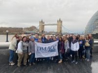 The 2020 Study Abroad group holds a DMACC banner in front of Tower Bridge.